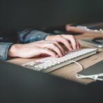 A person typing on a keyboard using technology expense management software.