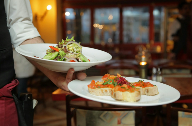 A person holding plates of food Description automatically generated