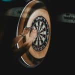 person picking dart pins on board